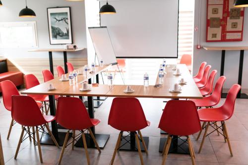 a conference room with a table and red chairs at Best Hotel Bordeaux Sud in Villenave-dʼOrnon