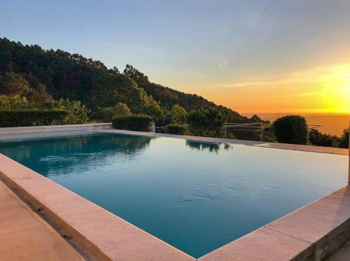 a swimming pool with a sunset in the background at Pera da Serra - Turismo no Espaço Rural in Lousã
