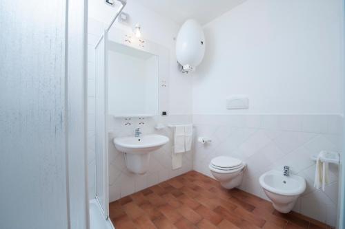 a white bathroom with a toilet and a sink at Residence S'incantu in Villasimius