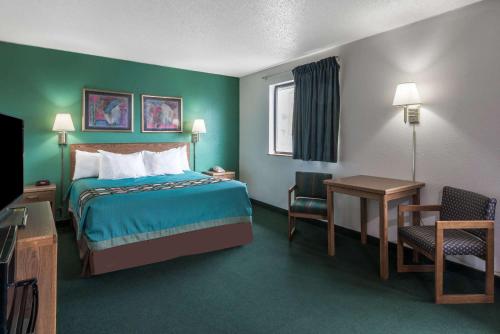 a hotel room with a bed and a desk and chair at Super 8 by Wyndham New Stanton in New Stanton