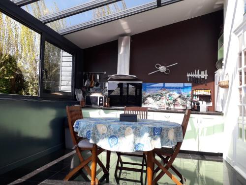 a kitchen with a table and chairs and windows at Ecrin de tranquillité - Centre Village in Barneville-Carteret