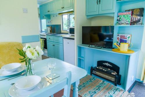 uma cozinha com armários azuis e uma mesa branca com flores em Wind In The Willows: Sleeps 4, Kitchen, bathroom, lounge, WIFI em Napton on the Hill