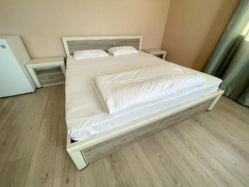 a bed with white sheets and pillows in a room at Resident Hotel Kaskelen in Kaskelen