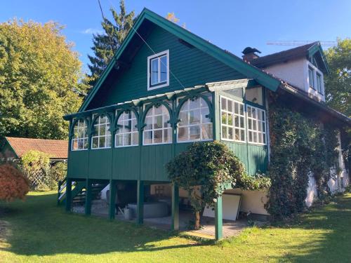 a green house with a green roof at Haus mit Sauna und privatem Badeteich in Anif bei Salzburg in Anif