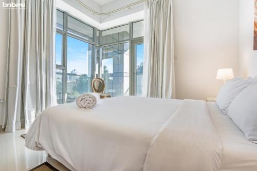 biała sypialnia z dużym łóżkiem i oknem w obiekcie bnbmehomes - Great Value Spacious Apartment w Moden Furniture - 103 w Dubaju