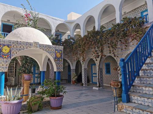 a courtyard of a building with stairs and plants at Hôtel Sindbad in Houmt Souk