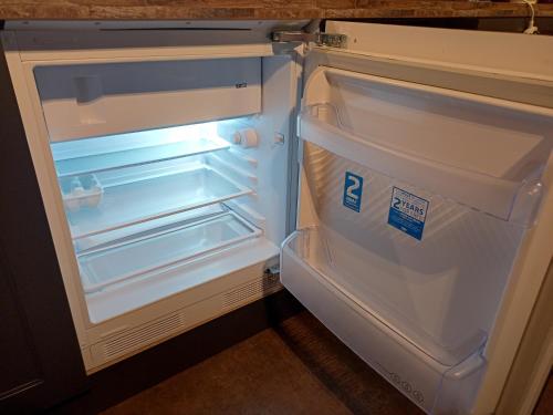 an empty refrigerator with its door open in a kitchen at Longbridge Cottage in Shepton Mallet