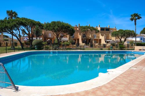 a large blue swimming pool with trees in the background at Casa Marisa Sancti Petri in Novo Sancti Petri