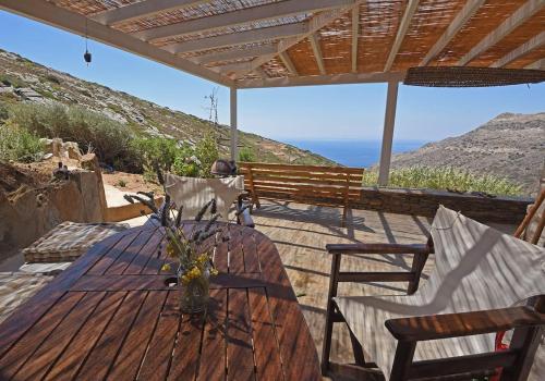 een houten tafel en stoelen met uitzicht op de oceaan bij Traditional stone house 1bedroom, sea view, Syros in Ano Syros