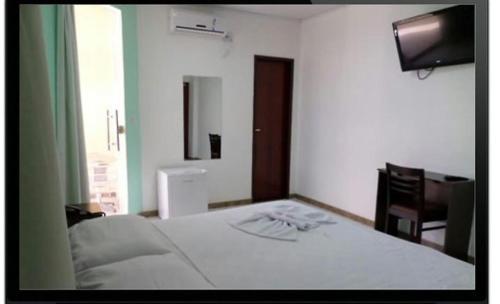 a bedroom with a white bed and a television at Hotel União in Pojuca