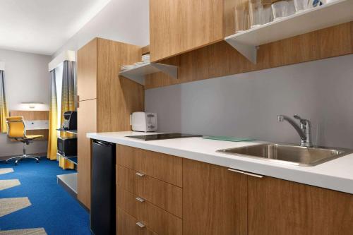 a kitchen with a sink and wooden cabinets at Microtel Inn Suites by Wyndham Lac-Megantic in Lac-Mégantic