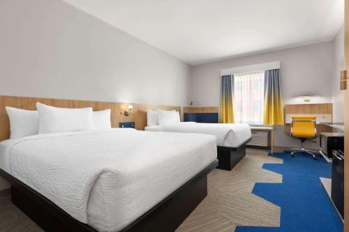 a hotel room with two beds and a desk at Microtel Inn Suites by Wyndham Lac-Megantic in Lac-Mégantic
