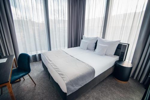 a hotel room with a bed and a chair and windows at Hotel Liberte 33 BW Premier Collection in Poznań