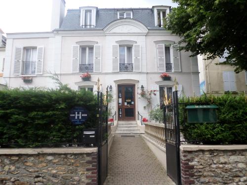 a white house with a gate in front of it at Hôtel Marie Louise in Enghien-les-Bains