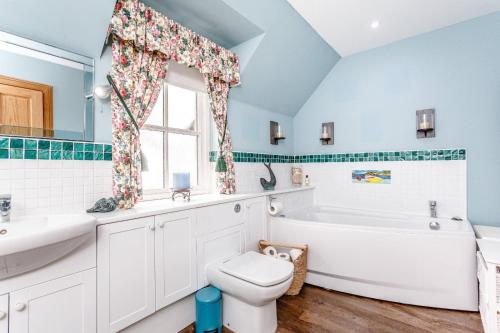 a bathroom with a tub and a toilet and a sink at Glenerrick House - Loch Ness country manor - hot tub and sauna in Whitebridge