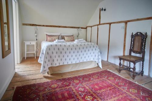 a bedroom with a bed and a chair and a rug at Rock Cottage in East Rudham
