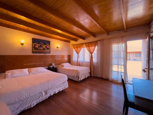 a bedroom with two beds and a table and a window at Ittai Hotel in San Pedro de Atacama