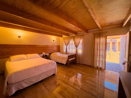una camera con 2 letti in una stanza con pavimenti in legno di Ittai Hotel a San Pedro de Atacama
