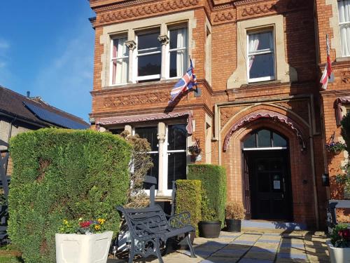 un edificio con una bandera y un banco delante de él en The Lismore Hotel en Banbury