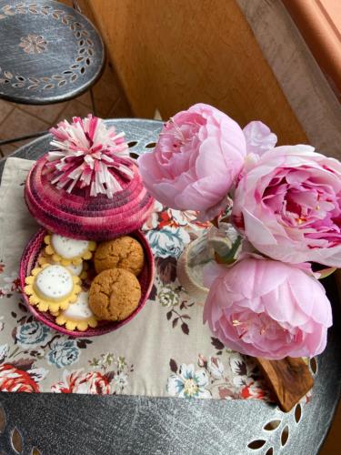 una mesa con dos flores rosas y galletas en ella en B&b Peonia orgosolo en Orgosolo