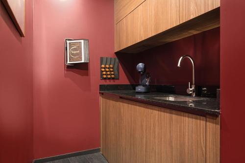 La salle de bains est pourvue d'un lavabo et d'un mur rouge. dans l'établissement Legend Majestic Superbe Love Room - Jacuzzi - Champagne - Romantisme - parking privé GRATUIT, à Mâcon