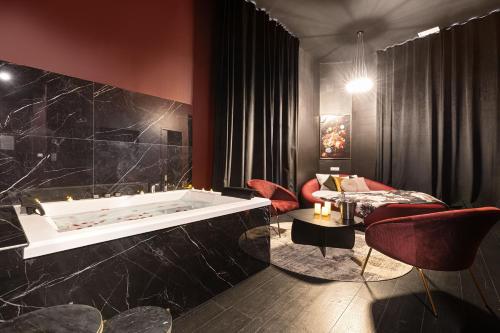 Cette chambre comprend une baignoire et des chaises rouges. dans l'établissement Legend Majestic Superbe Love Room - Jacuzzi - Champagne - Romantisme - parking privé, à Mâcon