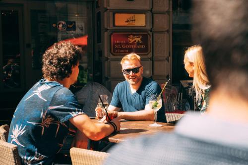 a group of people sitting at a table with drinks at Hotel St.Gotthard in Zürich