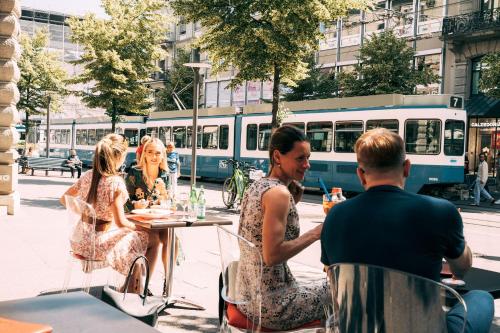 a group of people sitting at a table in front of a bus at Hotel St.Gotthard in Zürich