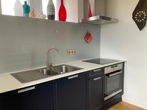 a kitchen with black cabinets and a sink at Maison Face à la Mer - Penhors in Pouldreuzic