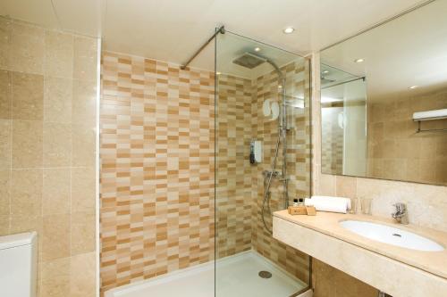 a bathroom with a sink and a glass shower at Sentido Fido Tucan - Beach Hotel in Cala d´Or