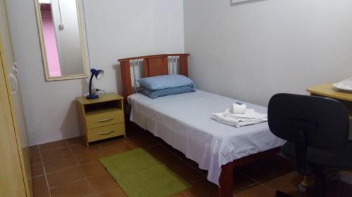 a small bedroom with a bed and a chair at Morada do Estudante in Pelotas