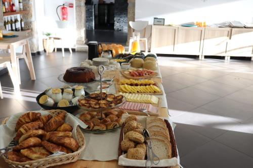 a table filled with different types of bread and pastries at Altitude Alojamento e Restauração in Belmonte