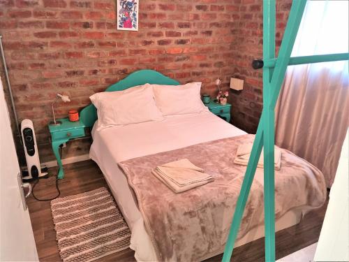 a small bedroom with a bed and a brick wall at GreenHouse Accommodation in Tulbagh