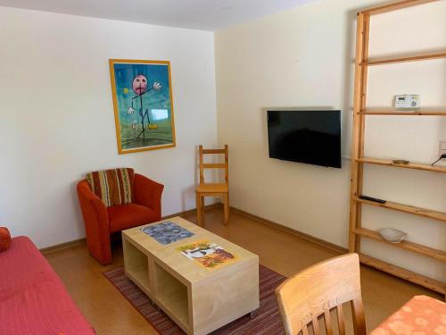 a living room with a table and a flat screen tv at Ferienbungalow 182 in Stahlbrode