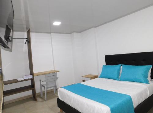 a bedroom with a blue and white bed and a chair at Hotel Monarka-Edificio in Popayan