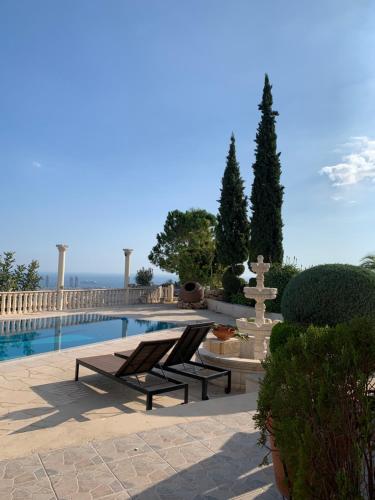 Ayia Phyla的住宿－Breath-taking Guest Apartment on Hill Top，一个带2把躺椅的游泳池和一个喷泉