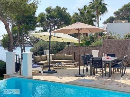 a patio with a table and umbrella next to a pool at Villa Sa Gavina water front in Santanyi