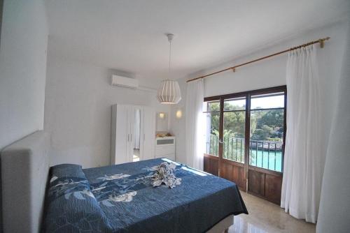 a bedroom with a blue bed and a large window at Villa Sa Gavina water front in Santanyi