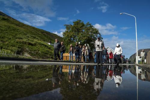 a group of people standing next to a body of water at Fisherman Guesthouse Sudureyri in Suðureyri