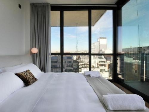 un grande letto bianco in una stanza con una grande finestra di Castillia, Bosco Verticale Apartment a Milano