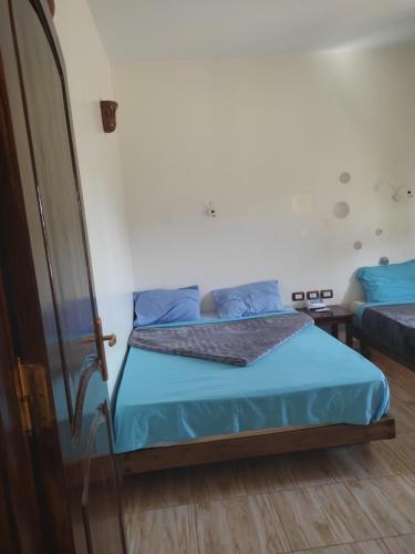 a bedroom with a bed with blue sheets and blue pillows at Habibi Nubian Guest House-Nubian Hospitality in Aswan