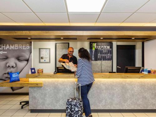 a woman standing at a counter in a store at ibis budget Paris Porte d'Italie Ouest in Le Kremlin-Bicêtre