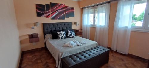 Schlafzimmer mit einem Bett mit einem schwarzen Kopfteil und einem Fenster in der Unterkunft Terraza La Falda in La Falda