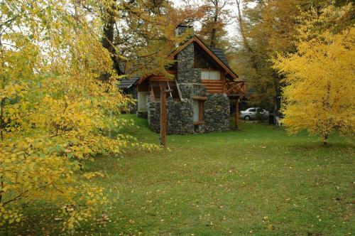 a stone house in the middle of a yard with trees at La Estancia Cabañas in Villa La Angostura