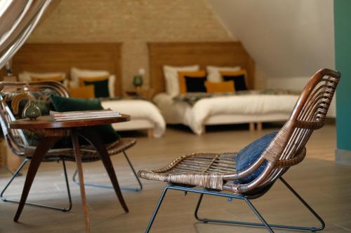 Le Fresne-CamillyにあるLe Domaine de l'Hostellerieの椅子2脚、テーブル1台、ベッド1台が備わる客室です。