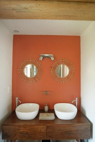a bathroom with two sinks and two mirrors on a wall at Le Domaine de l'Hostellerie in Le Fresne-Camilly
