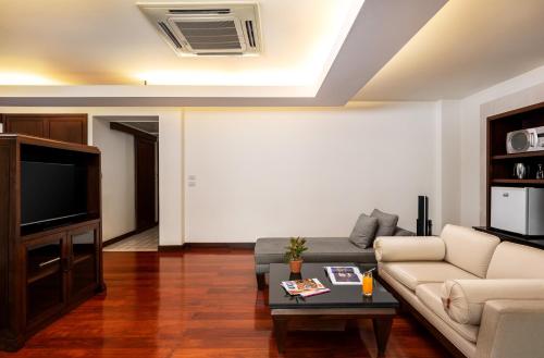 a living room with a couch and a tv at Patong Paragon Resort & Spa SHA Extra Plus in Patong Beach