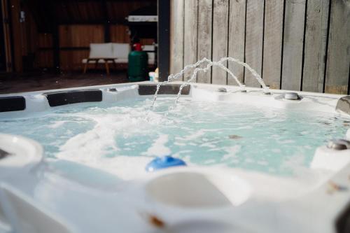 a jacuzzi bathtub with water pouring into it at Beavers Lodge. Luxury Property with Hot Tub in Tenby