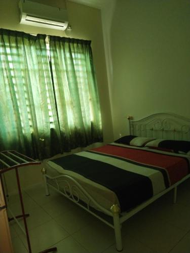 a bedroom with two beds and a window with curtains at Alma Homestay in Kampong Masjid