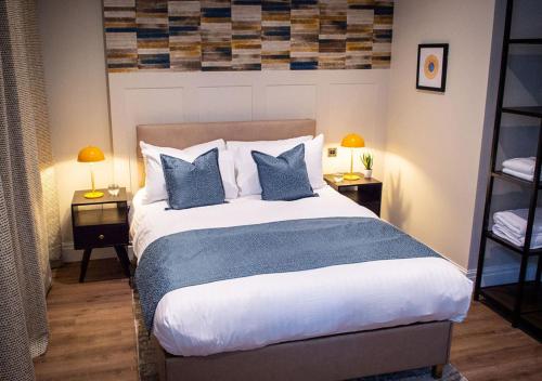 a bedroom with a large bed with blue pillows at The Gresham Aparthotel in Leicester